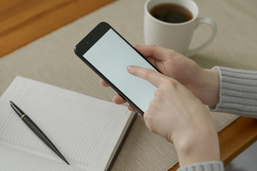 Woman using a smartphone in warm sweater. Close up
