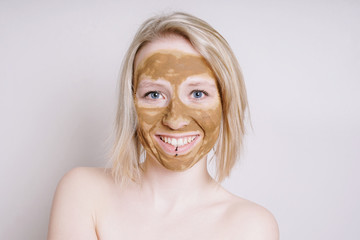young woman with healing earth or clay beauty facial mask, a natural ayurveda treatment for acne or...