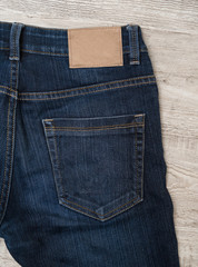 Back of blue jeans on wood background with brown leather label.