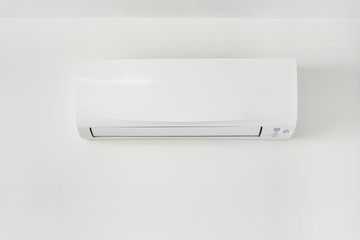 Air conditioner on white wall in area of room space.