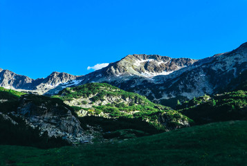 Beautiful alpine high mountains peak, blue sky background. Amazing Mountain hiking paradise landscape, summertime.