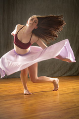 Young woman dancer dramatically falling in lavender skirt.