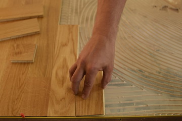 close up of worker installing wood parquet