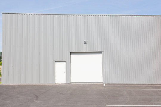 grey Warehouse building with blue sky and white door