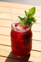 blueberry ice tea served in glass jar with fresh mint leaves and drinking straw