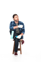 Fototapeta premium man in protective gloves sitting on chair with paint roller isolated on white background