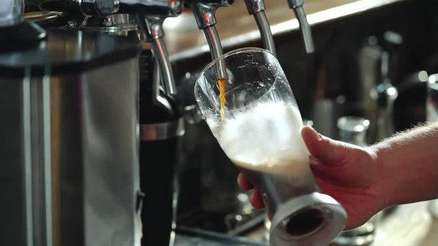 Bartender pours a dark beer in glass. Close-up.