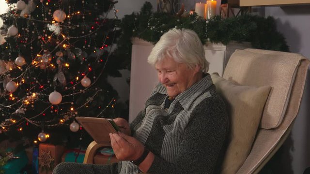 Elderly woman reads the message on a plate next to Christmas tree