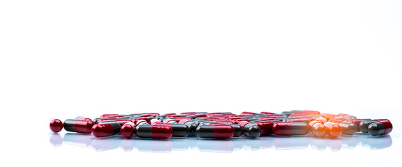 Pile of red and grey capsule pills isolated on white background with copy space. Flunarizine : drug for migraine prophylaxis treatment. Global healthcare concept. Pharmaceutical industry