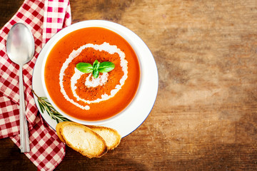 Tomato soup with croutons and fresh herbs  on rustic wooden background. Gazpacho cream soup. Top view. Copy space..