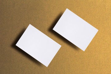 Photo of blank business cards. Mock-up template for branding identity. For graphic designers presentations and portfolios. Business cards stacks on golden textured paper background