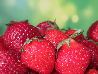 Fresh strawberries with leaves on a blurred green background. Red strawberry close-up