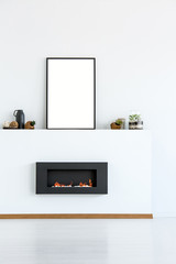 Mockup of empty poster above black fireplace in simple white living room interior. Real photo