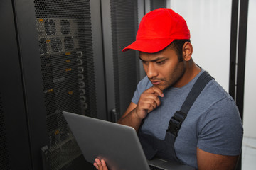 IT engineering. Musing IT engineer touching face and holding laptop