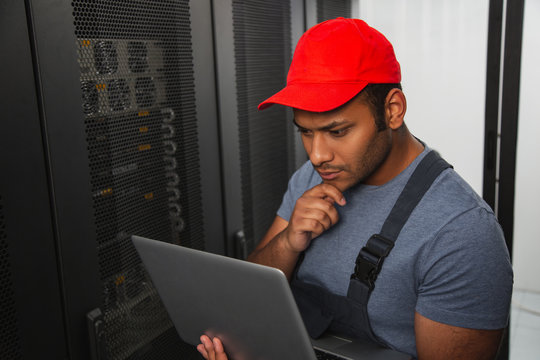 IT engineering. Musing IT engineer touching face and holding laptop - Powered by Adobe