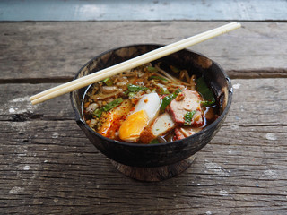 Spicy noodles with eggs In a bowl made of coconut shell. On the old wood table
