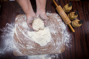 Woman cook sprinkling flour over cutting board. Cooking. Making bread on kitchen table. Cooking Process Concept