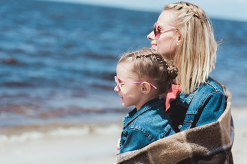 Fototapeta na wymiar stylish mother and kid in sunglasses looking at the sea