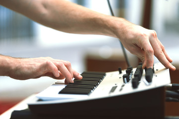 Obraz premium A synthesizer player during a concert moves knobs and controls the sound