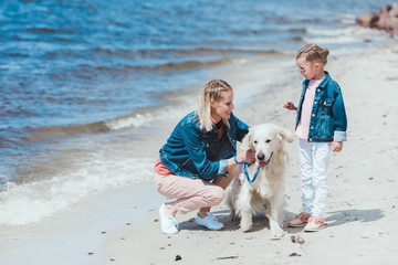 mother and kid walking with golden retriever dog on sea shore