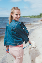 smiling woman walking with dog on sea shore