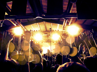Concert stage with cheerful fans, lens flare and distress effects are visible