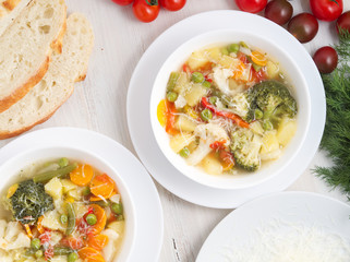 Minestrone soup. Vegetable soup with tomato, celery, carrot, zucchini, onion, pepper, broccoli. Top view, white table