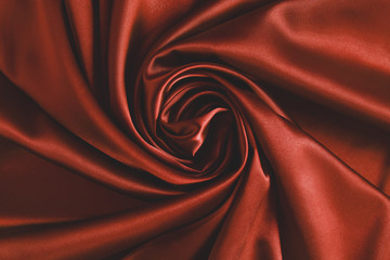 Obraz premium Close up of ripplesin shape of rose flower in red silk fabric. Satin textile background.
