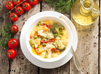 Minestrone vegetable soup with tomato, celery, carrot, zucchini, broccoli. Top view, gray rustic wooden table