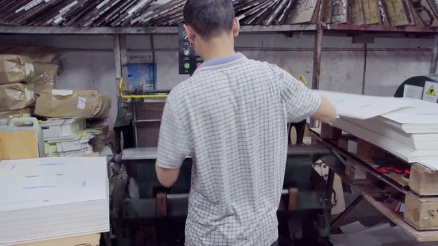 man prints on printing press company's logo on packaging products