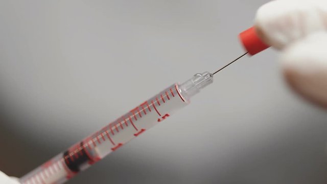Insulin addicted needs another shot. Doctor removes syringe cap to inject liquid