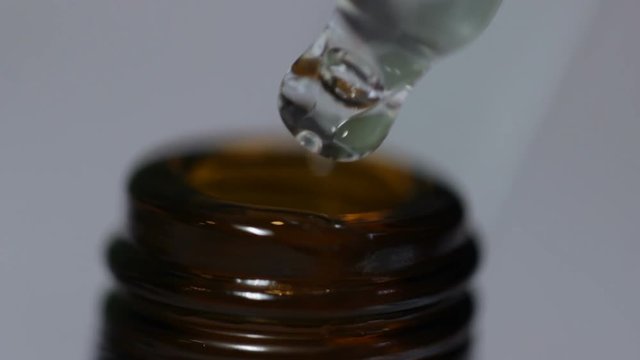 Glass bottle opens and pipe measures a few drops of clear liquid medicine