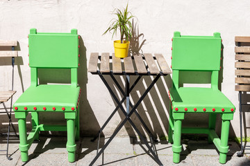 two green chairs and a table with a flower against the wall