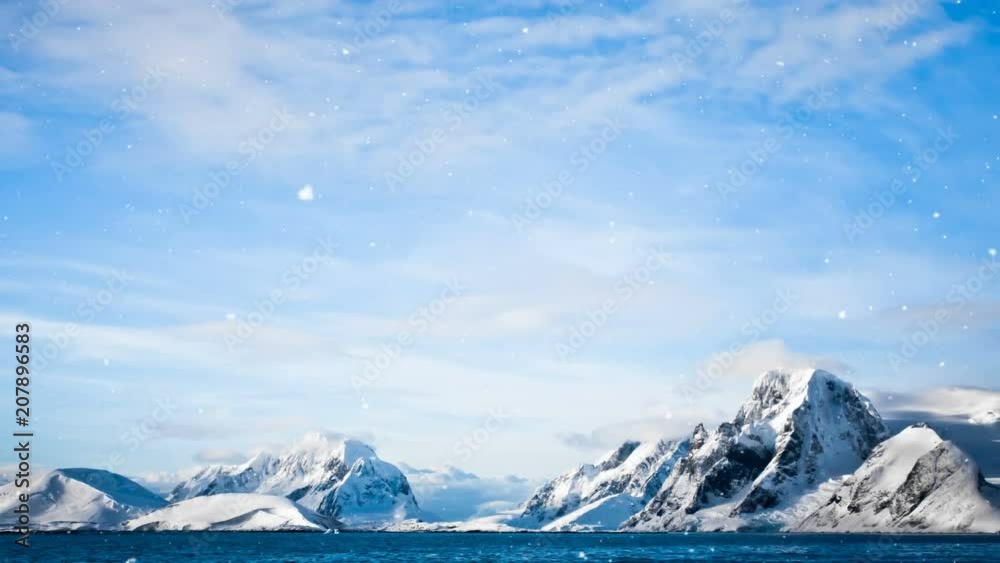 Wall mural antarctic nature. snow-capped mountains against blue cloudy sky with snow falling. majestic winter l