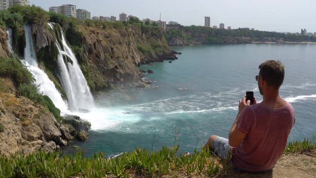 Selfie man. Male taking Self Photo on the Cliff near Waterfall