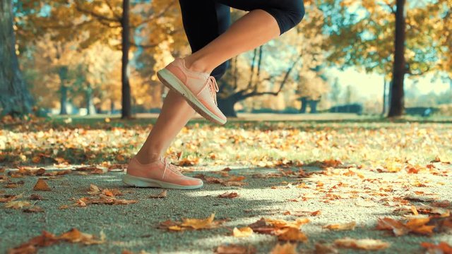 Fitness woman jumping rope. Female is jogging in sunny day light in the autumn trees background, girl training outdoors on fall day, 4K