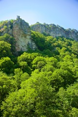 A mountain range not far from the city of Sochi. High rocks and a cliff beneath them. Eagle rocks. Green forest below.
