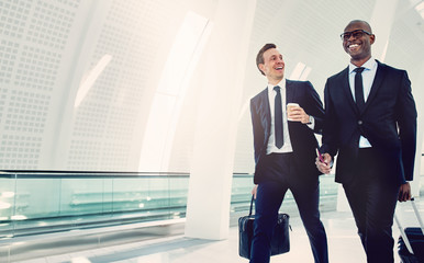 Smiling businessmen walking through an airport talking together