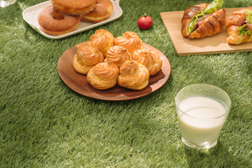 Healthy picnic for a summer vacation with freshly baked croissants, fresh fruit and fruit salad, sandwiches and a glass of refreshing orange juice laid out on a red and white checked cloth and hamper