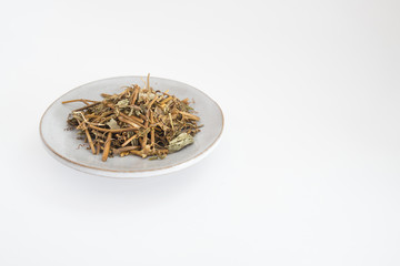 Dried tea leaves placed on a plate on a white background.