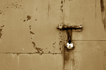 Old padlock on metal gate in brown color.