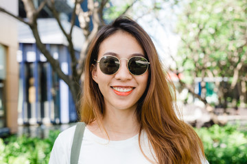 Close up of young Asian woman smiling in the garden enjoying her city lifestyle on weekend morning. Young woman with her weekend city lifestyle in garden. Outdoor activity and city lifestyle concept.