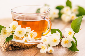 Fototapeta na wymiar Glass cup of green tea with white jasmine flowers
