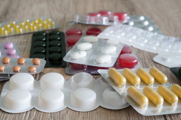Medical pills of different sizes, shapes and colors on a table