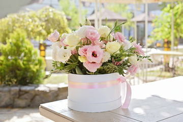 flower arrangement in white hat box on the table at summer terrace of restaurant