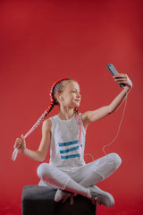 Adorable little girl taking a photo of herself with a smartphone.Beautiful little girl listening to...