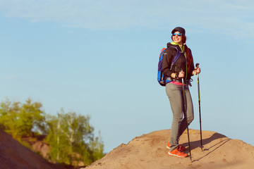 Picture of tourist woman with walking sticks and with backpack on hill