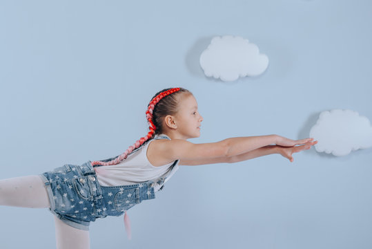 Stylish teenage girl is enjoying her modern kanekalon hair. little girl in fashionable denim overalls. - Powered by Adobe