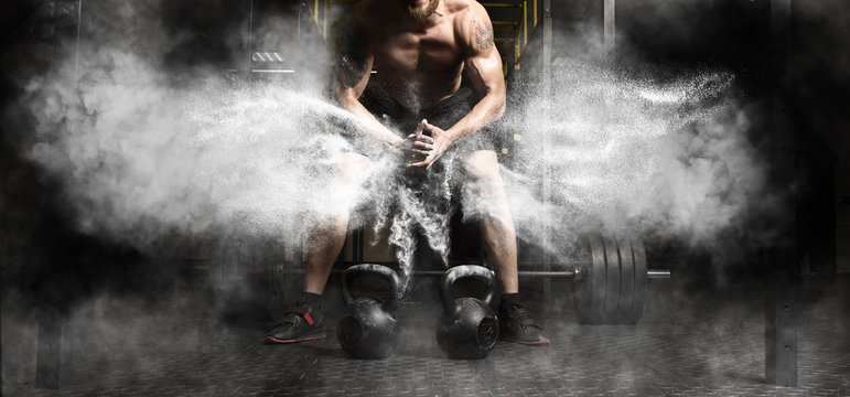 Fototapeta Muscular man workout with kettlebell at gym