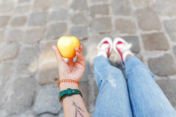 A woman tourist sits on a cobbles in the city and has an apple snack, travelers rest and diet concept
